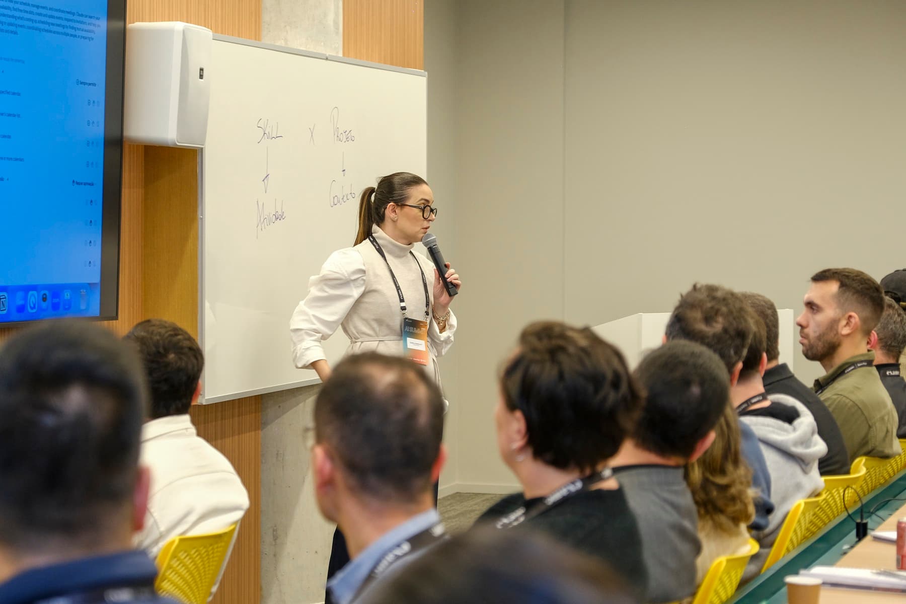 Izabela Anholett palestrando para uma turma em sala de treinamento
