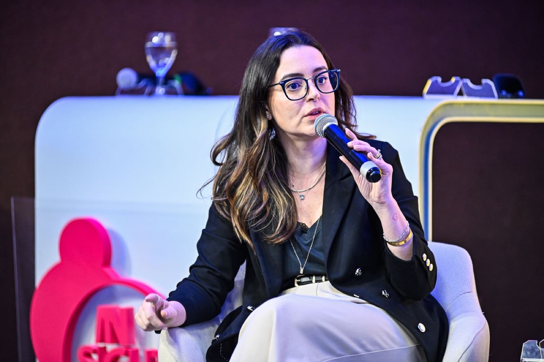 Izabela Anholett falando ao microfone em um palco